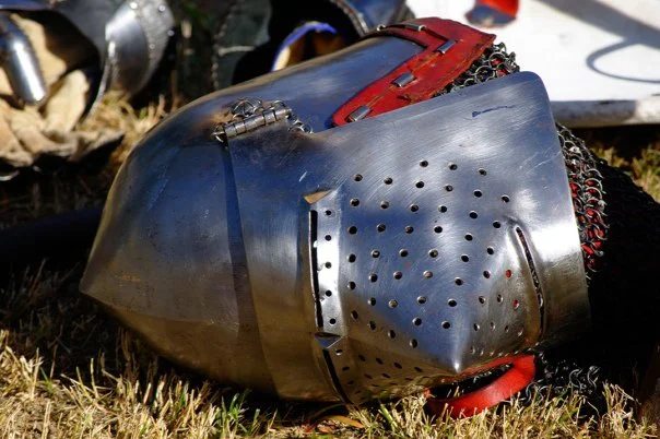 The objects left lying between bouts tell a different story than the combat itself. A helmet in the grass is a portrait of its wearer.