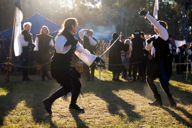 Late afternoon light and two people fighting with rapiers. I did not manufacture that image — I just showed up at the right time and stayed still.