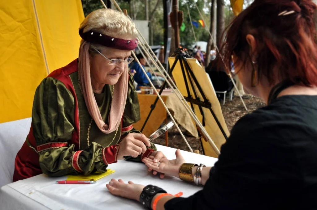 The market stalls are where the festival breathes. Combat is spectacle — but a palm reader leaning over a visitor's hand is a quiet portrait of belief.