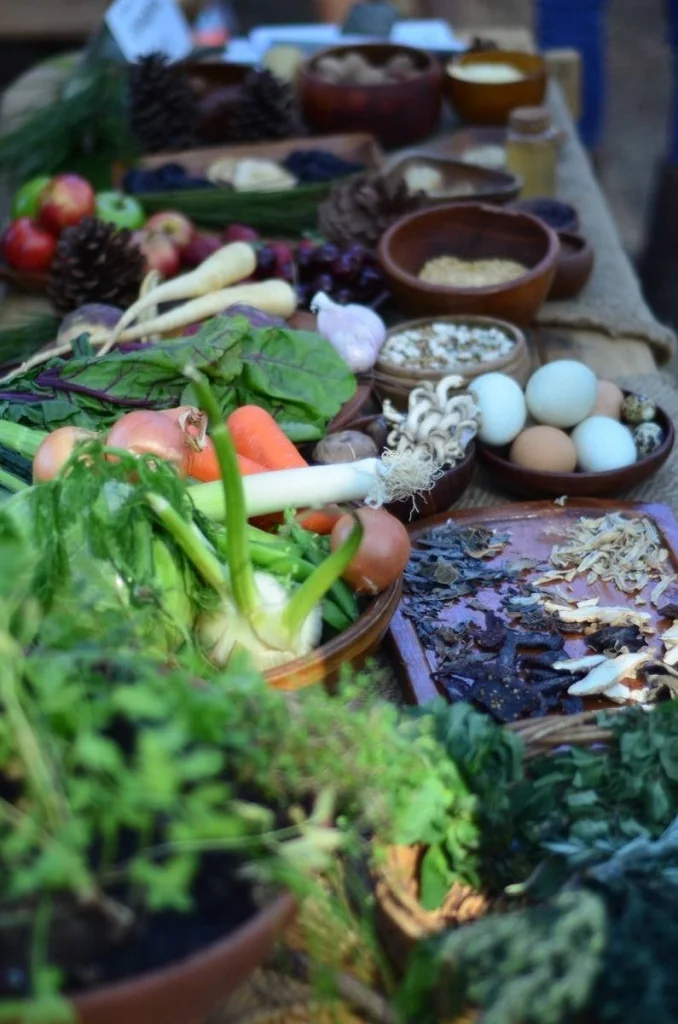 A table of medieval food — vegetables, eggs, herbs, dried mushrooms — is a still life that required no arrangement. It was already a painting.