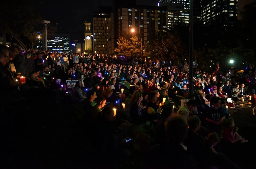 From the edge of the park, the crowd looked like a field of slow stars. The city skyline above it was entirely indifferent.