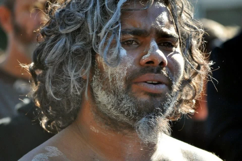 White ochre on skin in afternoon light. This is a face that knows exactly where it comes from.