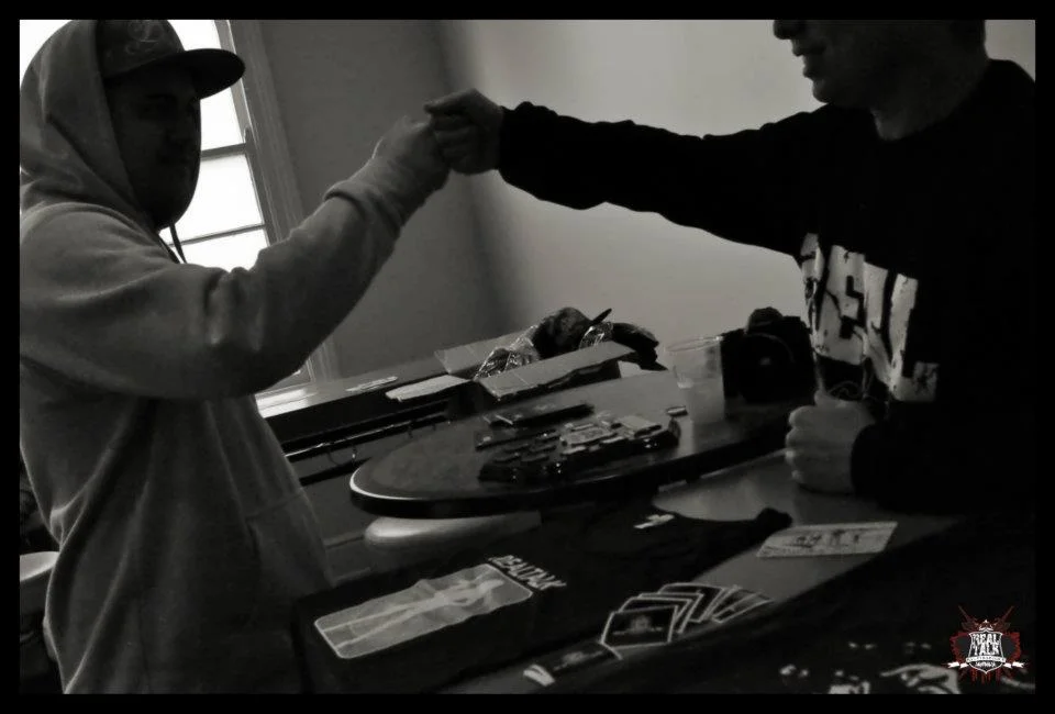 The fist bump over the merch table. Before any battle starts, there is this — the acknowledgement that you are both here for the same reason.