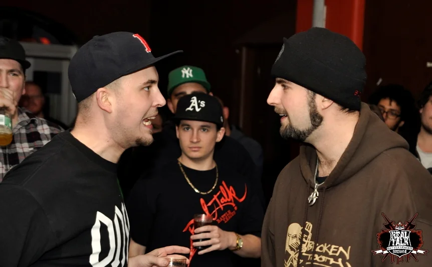 Two battlers facing off before the round starts. The crowd between them reads their faces for signs of what is about to happen.
