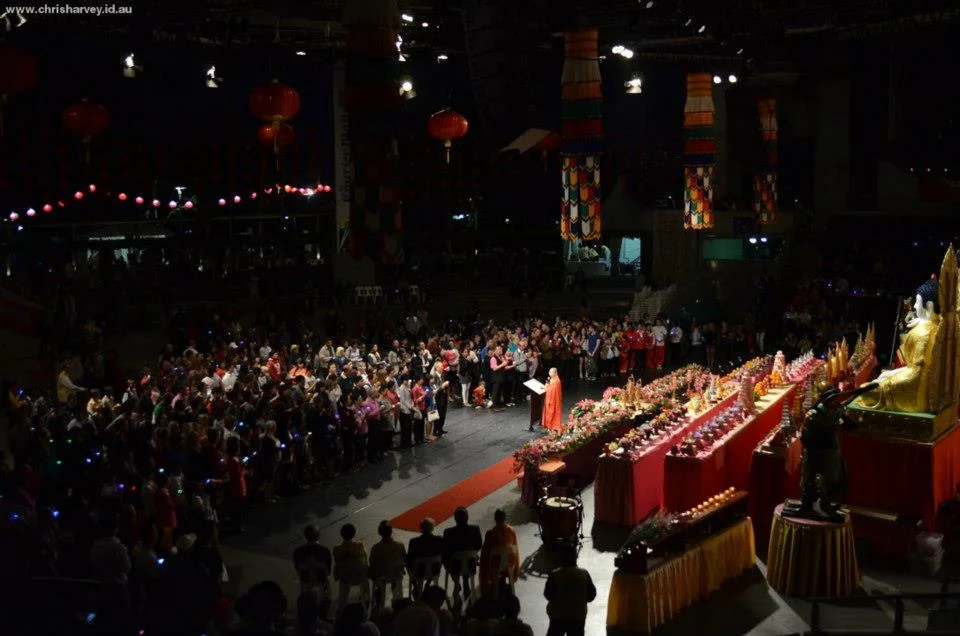 Thousands of people standing in a darkened hall, holding small lights, while lanterns hang from the ceiling. Scale changes everything.