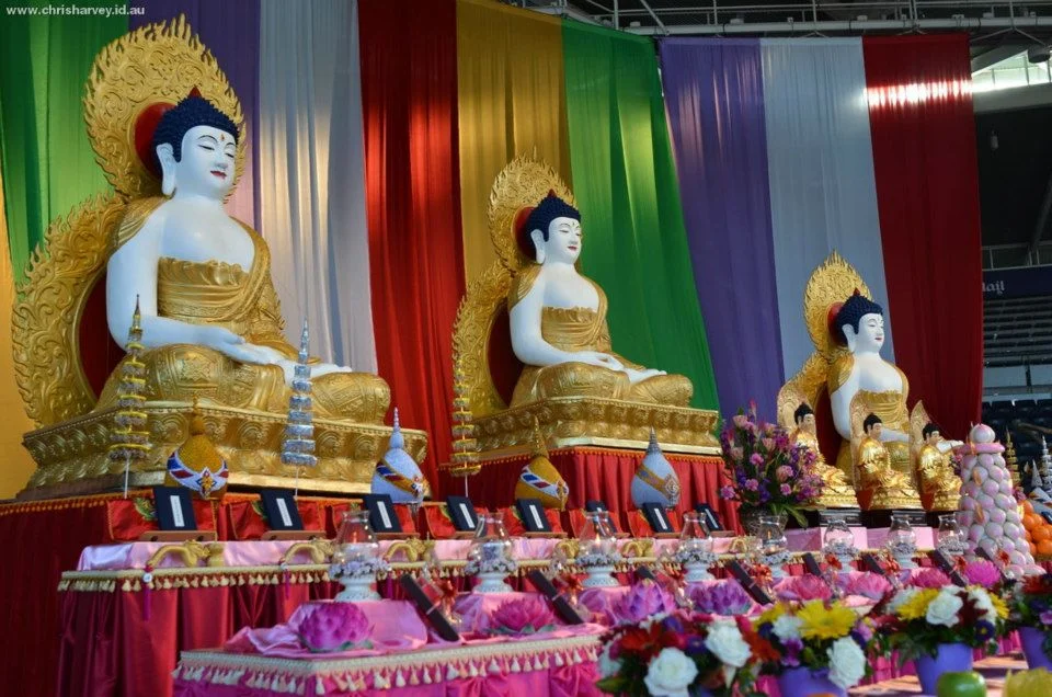 Three identical statues in diminishing perspective, each against a different colour of silk. The symmetry is the subject.