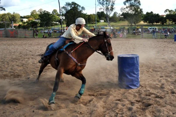 Horse and rider at full speed around a barrel, the sand kicking up behind them. The timer is running. Everything is committed.