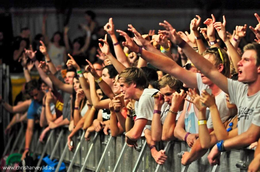 Arms raised along the barrier, every person reaching toward the same thing. The energy at the front of a crowd is unlike anywhere else.
