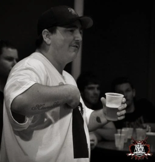 The cup in one hand, the other pointing. The casual confidence of someone who knows exactly what they're doing.