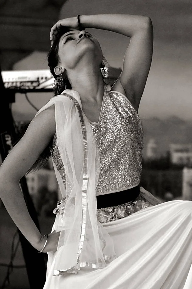 Arms raised, head back, completely in the movement. The costume becomes architecture when the body is fully extended.