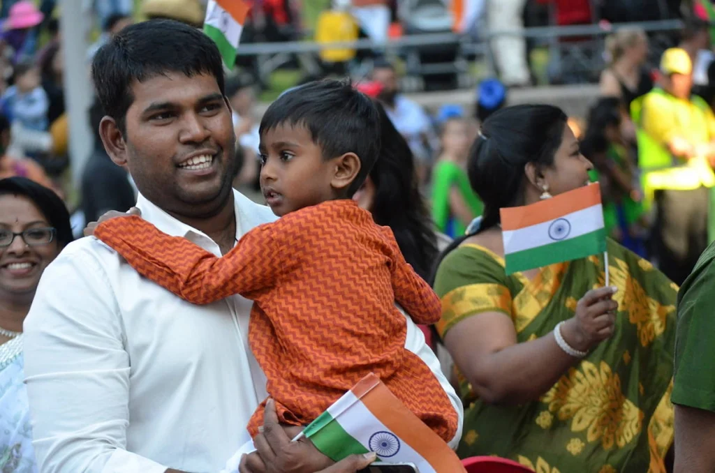 Father and child at the celebration, both holding the flag. The child is more interested in where it came from.