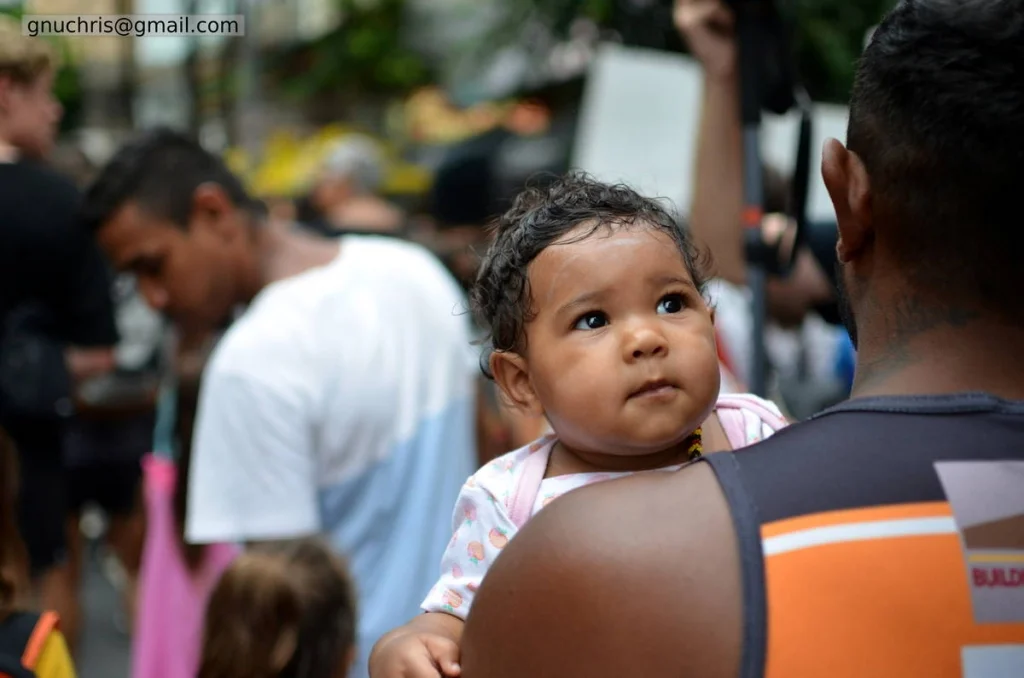 The baby on the father's shoulder, looking up at everything with no fear of it. The youngest person at the rally, taking it all in.