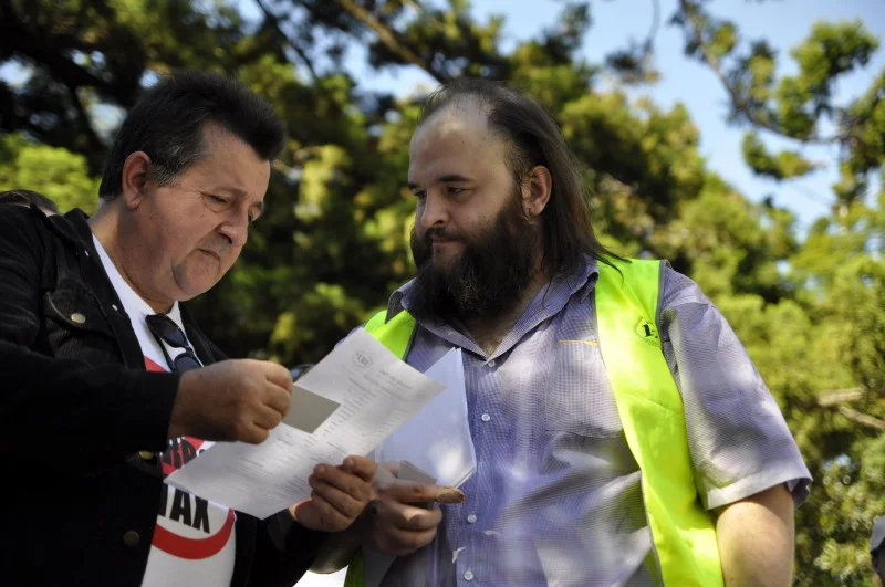 Between the speeches, two people read the same piece of paper. The politics is in the background. The moment is just two people deciding something.
