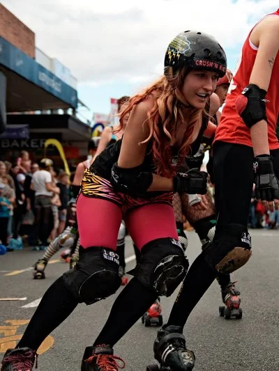 Low and leaning into the corner, helmet on, completely focused. The roller derby skater in full flight is one of the more kinetic subjects in street photography.