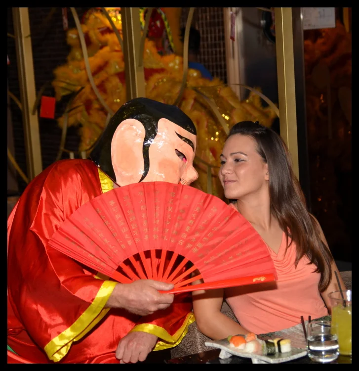 The God of Fortune leans over the table with a red fan, and the diner plays along perfectly. The restaurant is suddenly a different kind of space.