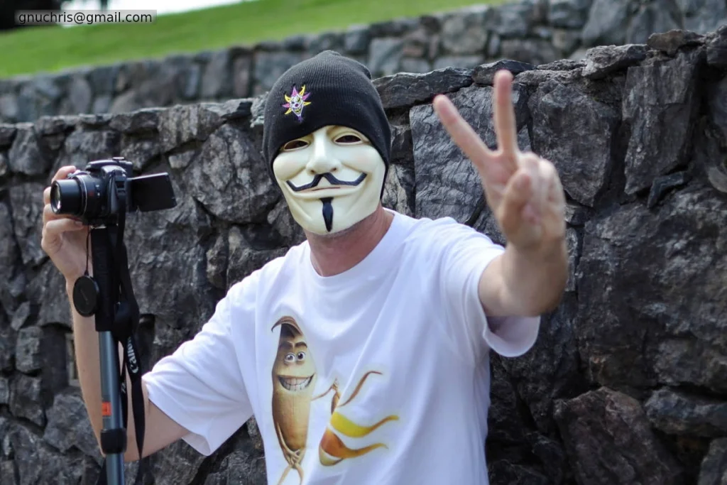 Masked, camera in hand, peace sign to the camera. The photographer is part of the event. This has always been true.