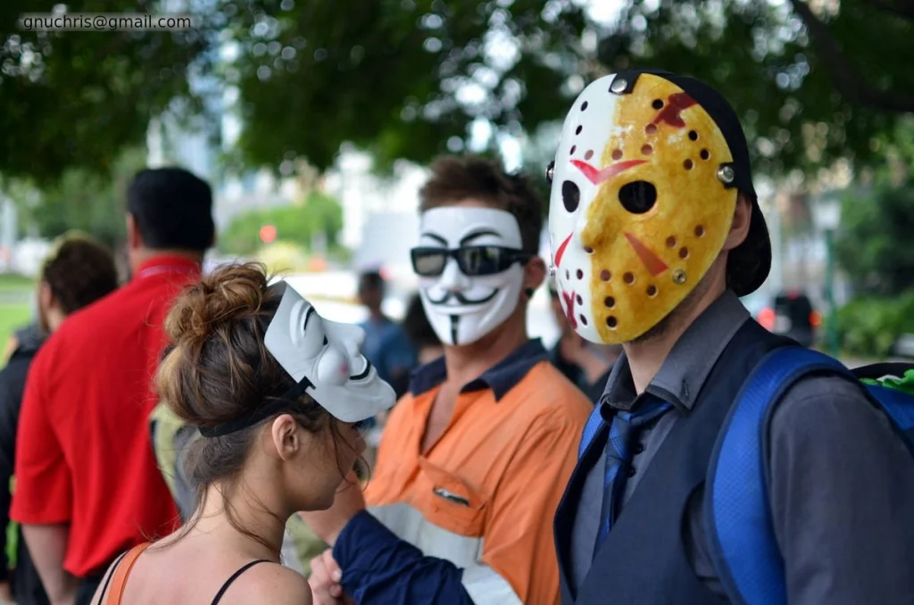 Three masks in a group — two Guy Fawkes, one Jason. The hockey mask is an interesting choice at an Anonymous event.
