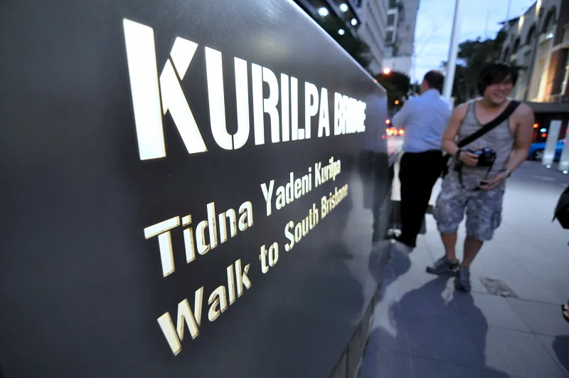 The name in gold on black: Kurilpa Bridge, Tidna Yadeni Kurilpa, Walk to South Brisbane. Three languages naming the same crossing. That is a photograph before you even look up.