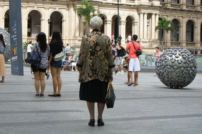 The back of someone watching a parade can tell you as much as their face. The set of the shoulders, the stillness, the way they have planted themselves — that is a portrait.